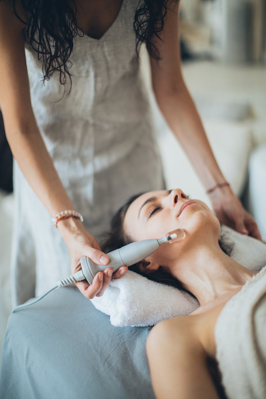 a woman lying down with a laser device on her face